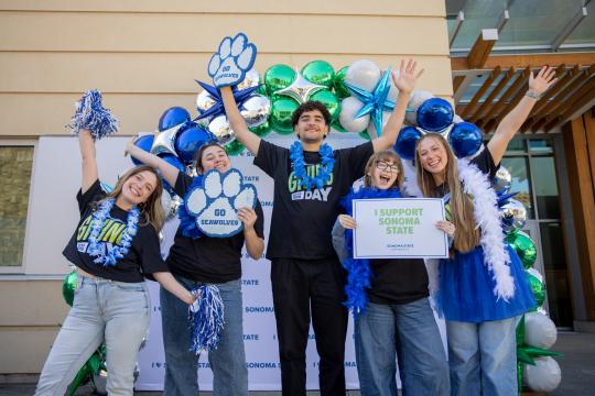 Five students holding hands up in the air chering and holding an I Support SSU sign